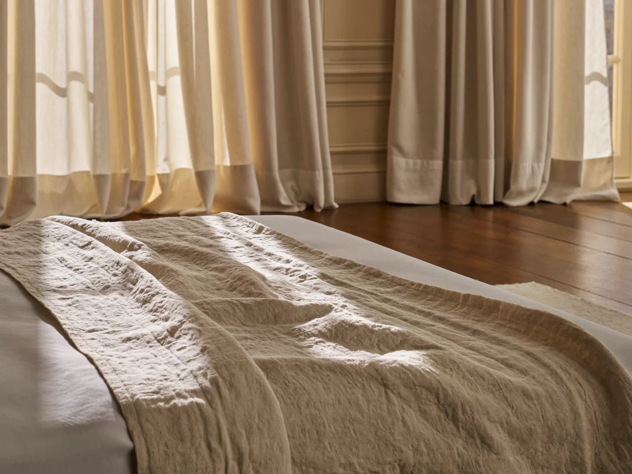 Chambre lumineuse avec un lit habillé de linge naturel en lin, lumière du matin