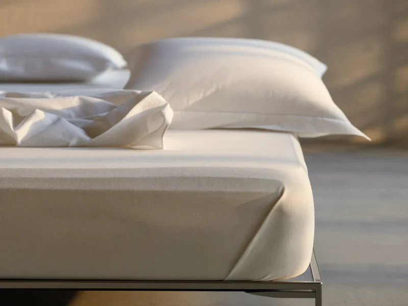 Drap-housse en percale blanche et deux taies d'oreiller sur un coin de matelas